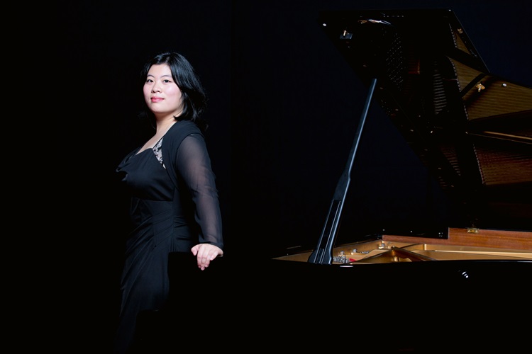 Cynthia Liem in zwarte avondkledij naast een zwarte vleugel op het podium