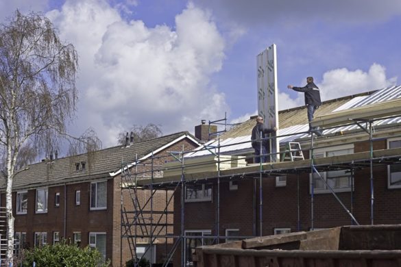 Dakdekkers werken aan isolatie van een rij woningen