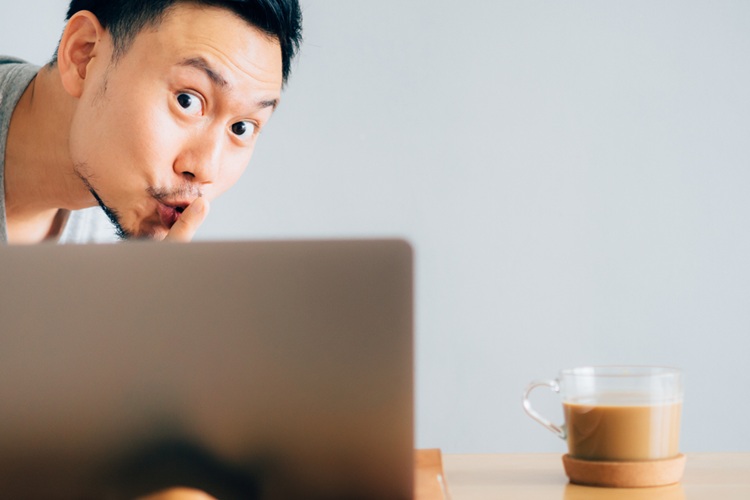 Aziatische man kijkt over laptop heen