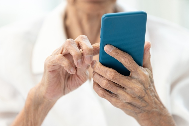 Closeup van de handen van een oudere vrrouw met een smartphone