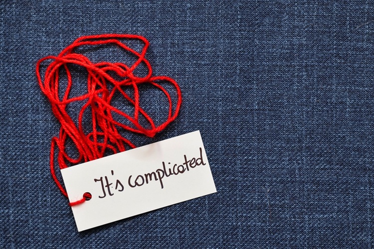 Blauwe achtergrond met rood kluwen garen. Kaartje eraan met tekst 'It's complicated'