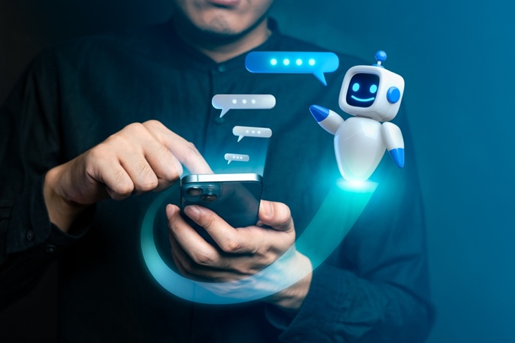Chatbot poppetje naast hand van man die mobiele telefoon vasthoudt
